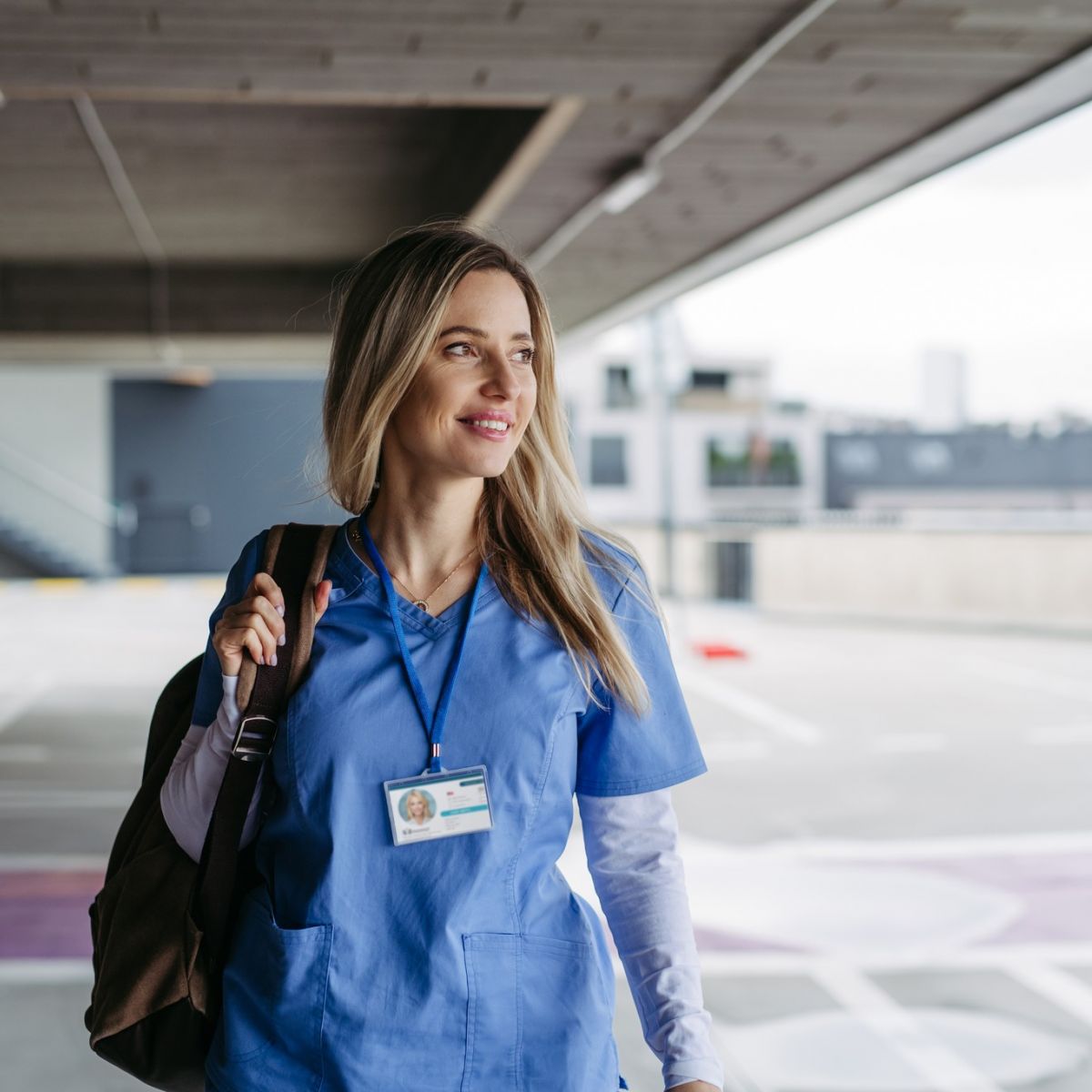 Young female nurse walking to work in a parking garage