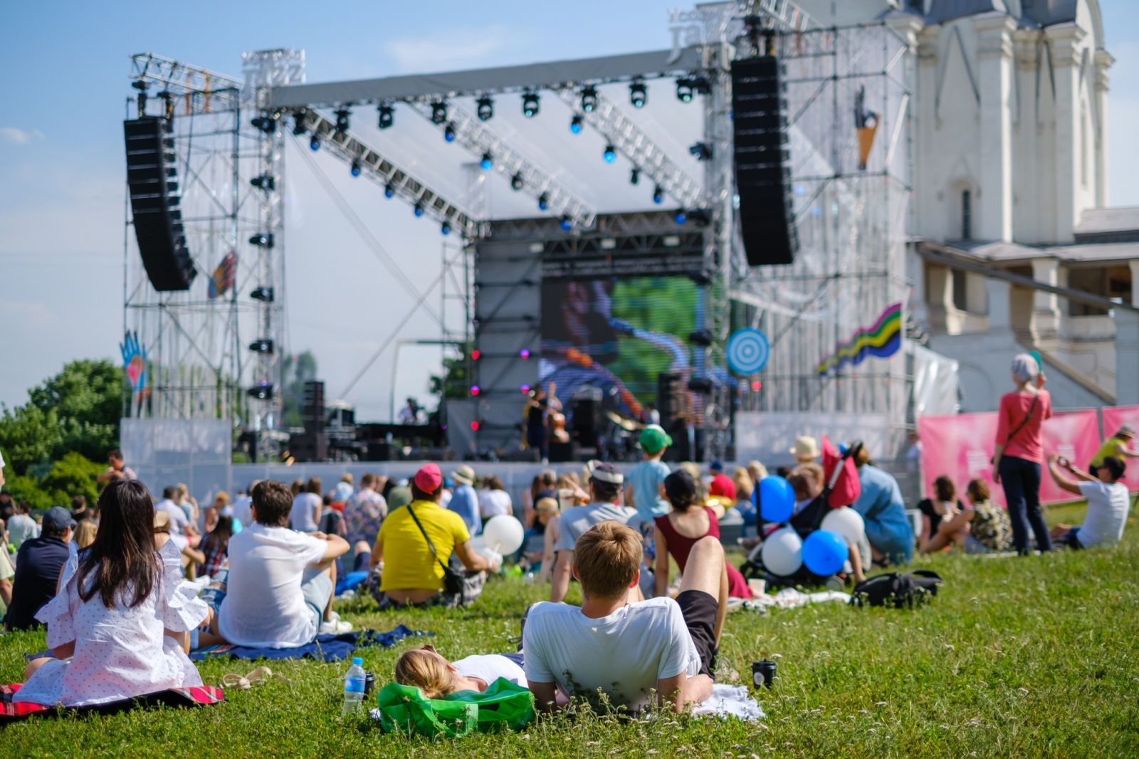 People outside watching a live concert on a stage in a park