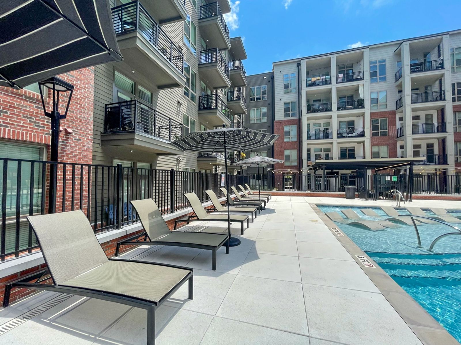 Van Alen apartments resort-inspired pool with in-pool lounge seating and surround lounge chairs and umbrellas